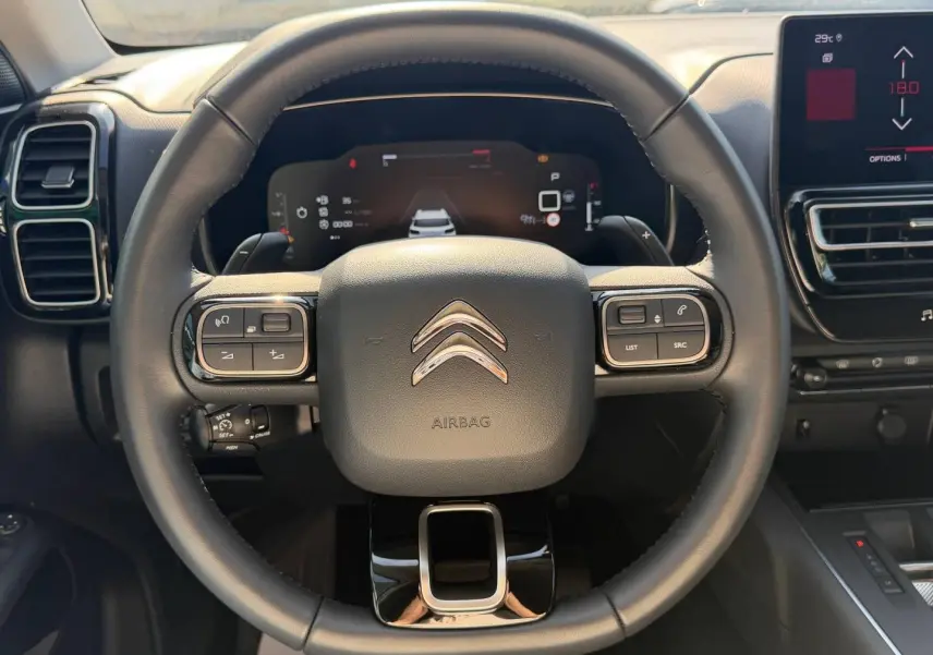 Vue rapprochée du volant cuir multifonction noir du Citroën C5 Aircross avec tableau de bord digital en arrière-plan.