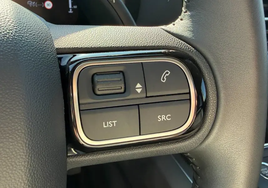 Gros plan sur les commandes multifonctions gauche du volant cuir du Citroën C5 Aircross blanc Okénite 2025.