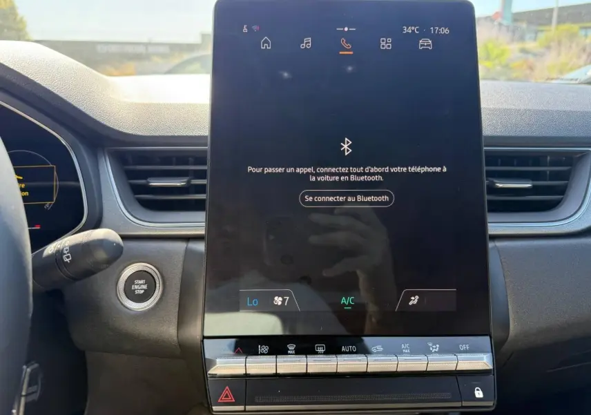 Vue intérieure centrée sur l'écran tactile vertical du tableau de bord du Renault Captur 2025, avec bouton start visible à gauche.