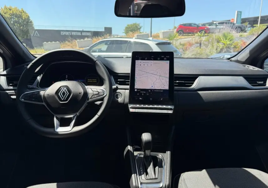 Vue intérieure avant du Renault Captur 1.6 E-Tech gris Rafale, avec volant multifonction et écran tactile central vertical.