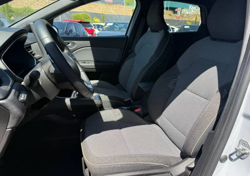 Vue intérieure côté conducteur du Renault Captur 2025, sièges gris avec accoudoir central et volant multifonction.