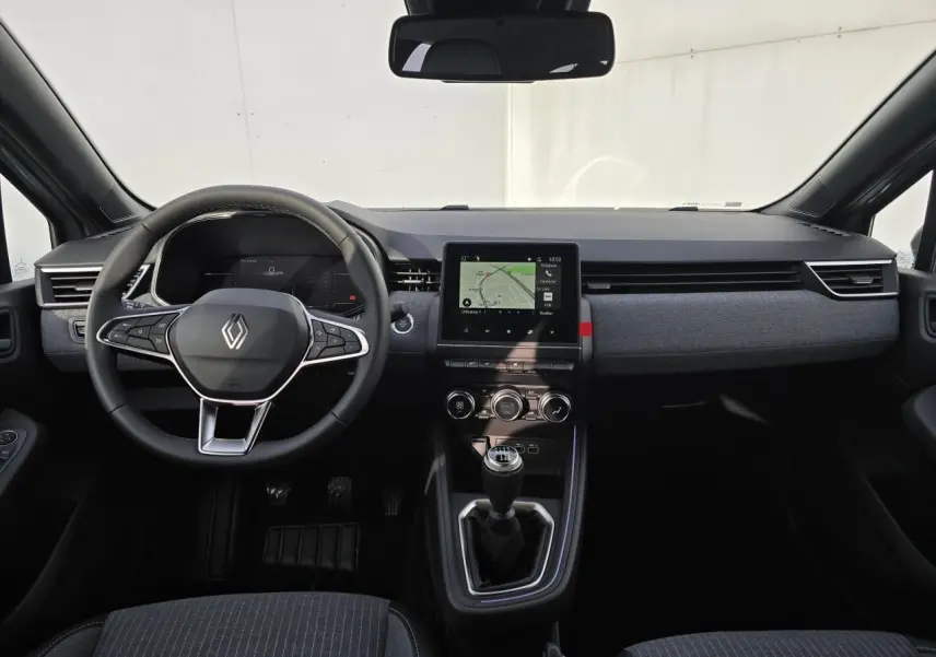 Vue intérieure avant de la Renault Clio V 2025 gris Rafale Métal avec tableau de bord moderne et boîte manuelle.