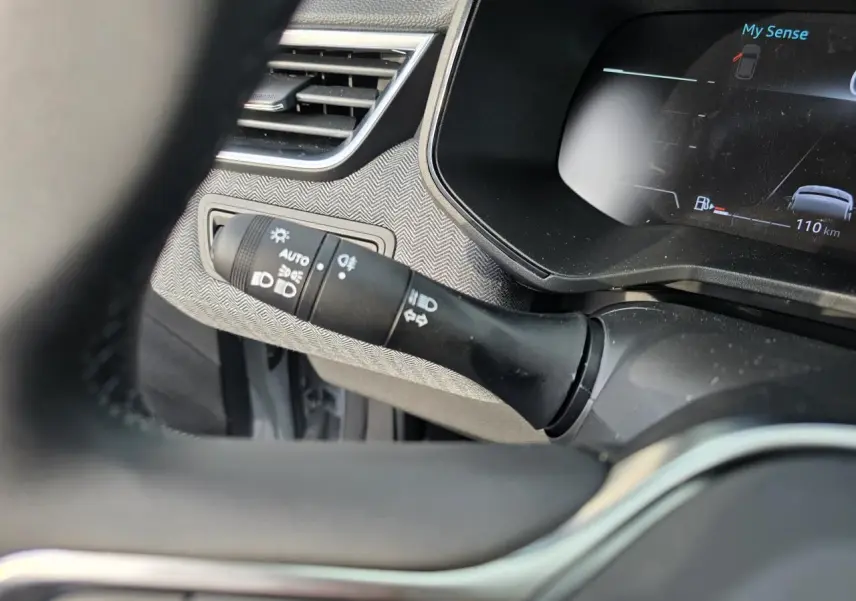 Détail du commodo d’éclairage et tableau de bord numérique avec affichage du mode My Sense dans une Renault Clio gris Rafale.