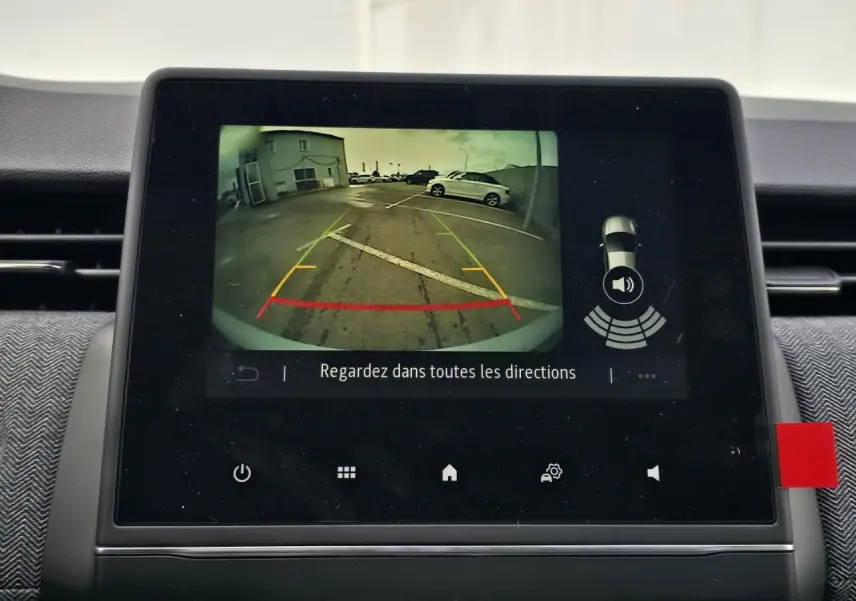 Écran multimédia affichant la caméra de recul d'une Renault Clio gris Rafale, vue arrière avec lignes de guidage colorées.