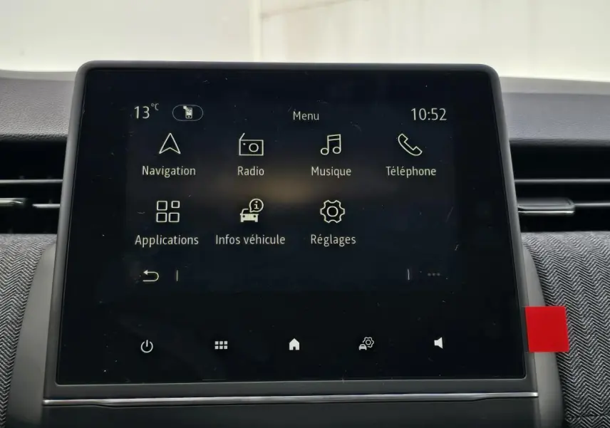 Écran tactile central de la Renault Clio V 2025 affichant le menu principal avec navigation et radio, intérieur gris.