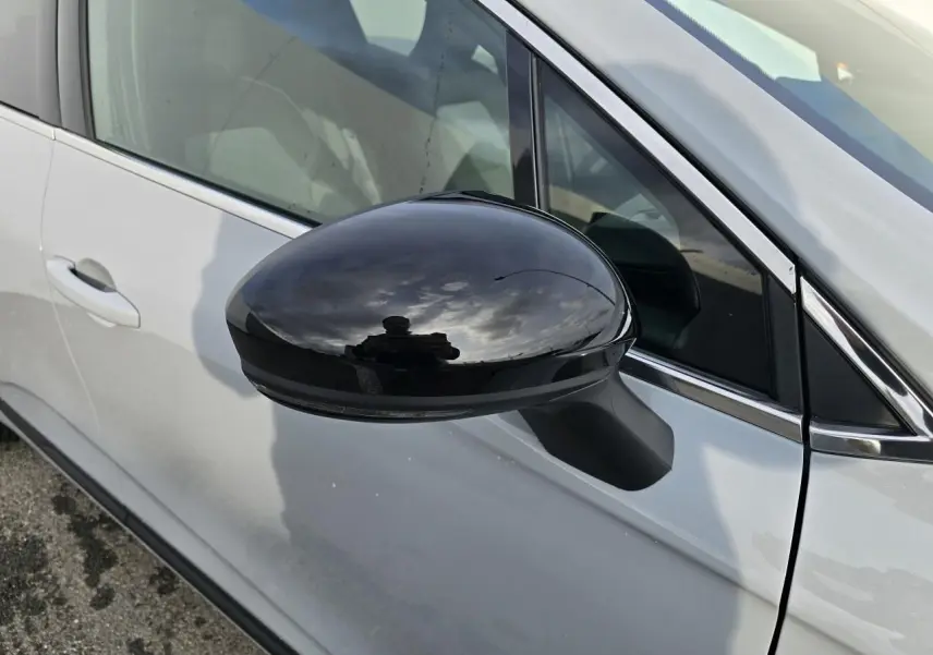 Rétroviseur noir brillant côté gauche d'une Renault Clio V gris Rafale métal, avec contour de vitres chromé visible.