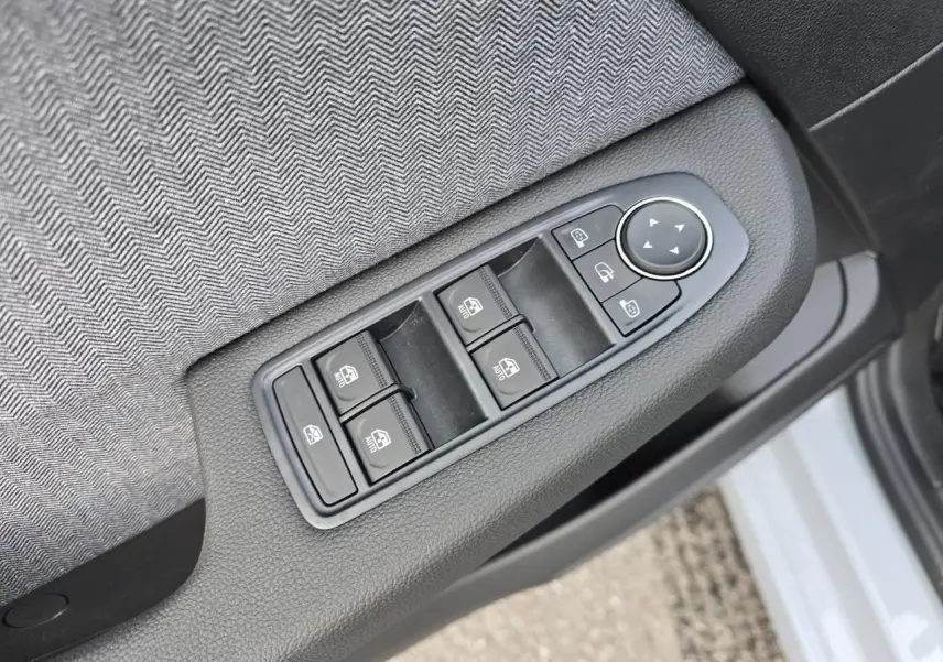 Gros plan sur les commandes des vitres et rétroviseurs côté gauche d'une Renault Clio gris Rafale métal.