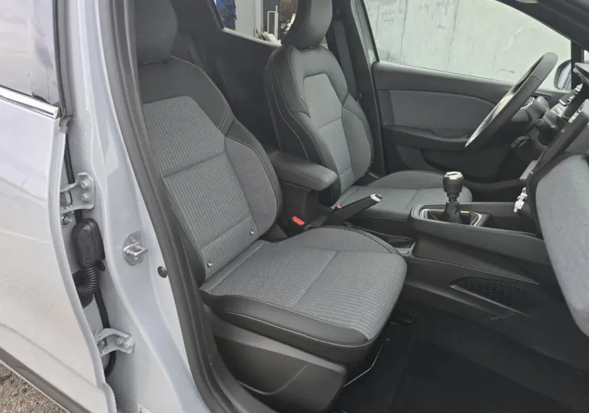 Vue intérieure côté gauche de la Renault Clio 2025 gris Rafale, sièges tissu gris avec coutures blanches et levier de vitesse manuel.