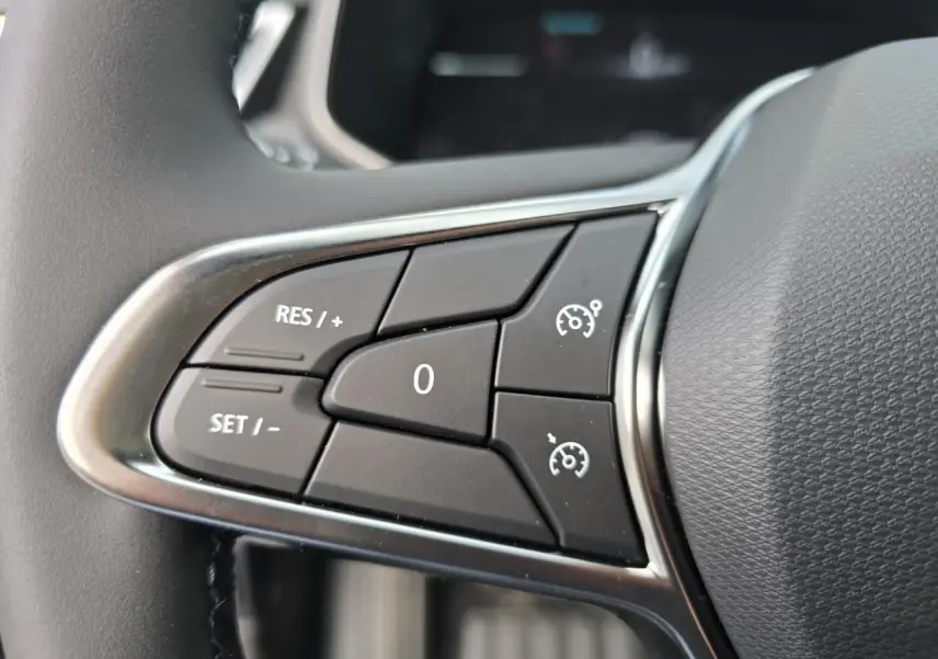 Gros plan sur les commandes de régulateur de vitesse au volant de la Renault Clio V gris Rafale métal.