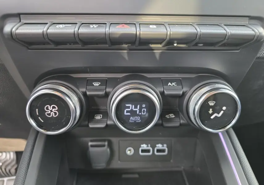 Gros plan sur la console centrale de la Renault Clio 2025, boutons de climatisation et ports USB visibles.
