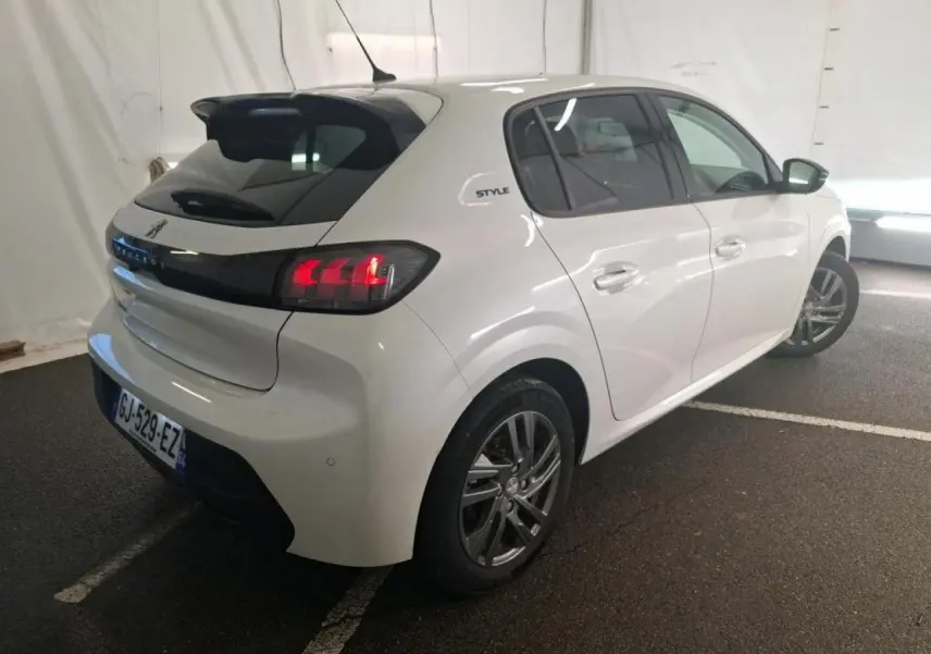 Peugeot 208 blanche vue 3/4 arrière droit, avec bandeau noir brillant entre feux et jantes alliage 16 pouces.