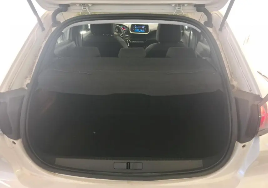Vue arrière ouverte sur le coffre d'une Peugeot 208 blanche, avec intérieur noir et tableau de bord visible.