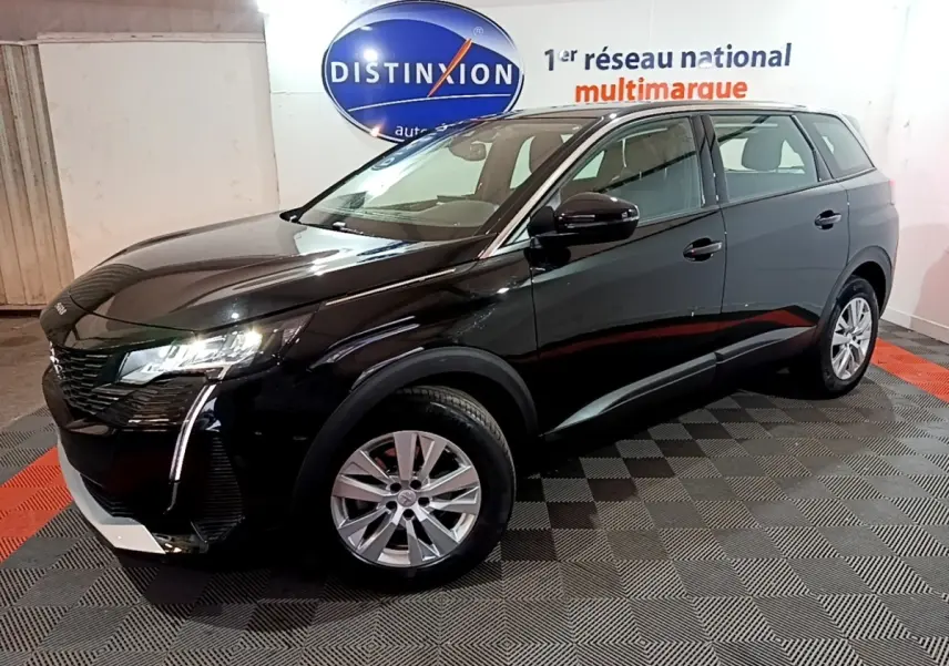 Peugeot 5008 noir vue 3/4 avant droit, avec feux LED et jantes alliage dans un showroom intérieur.