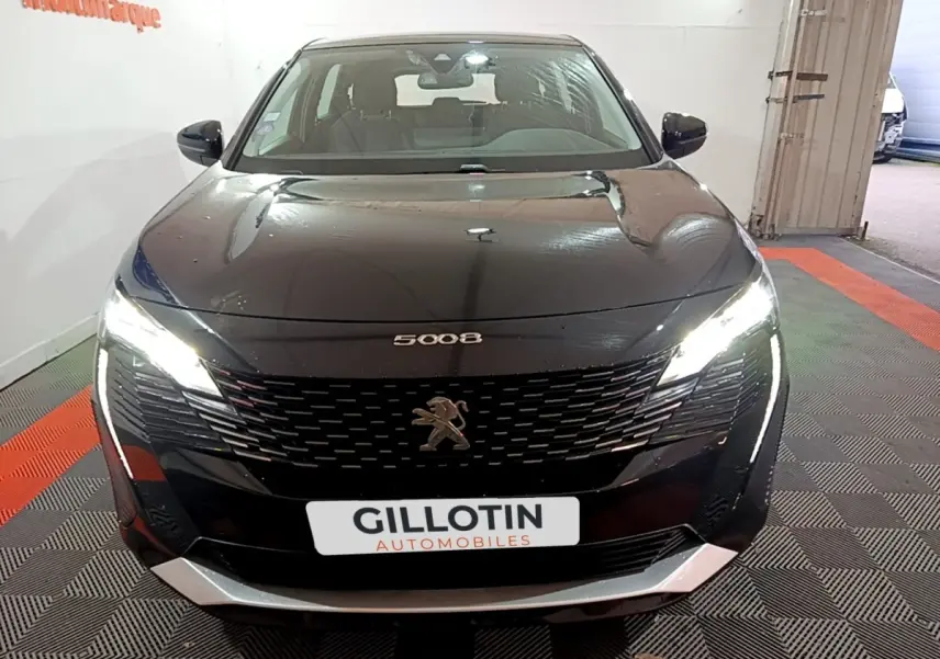 Vue avant d'un Peugeot 5008 noir 2021 avec phares LED allumés et calandre distinctive en concession.