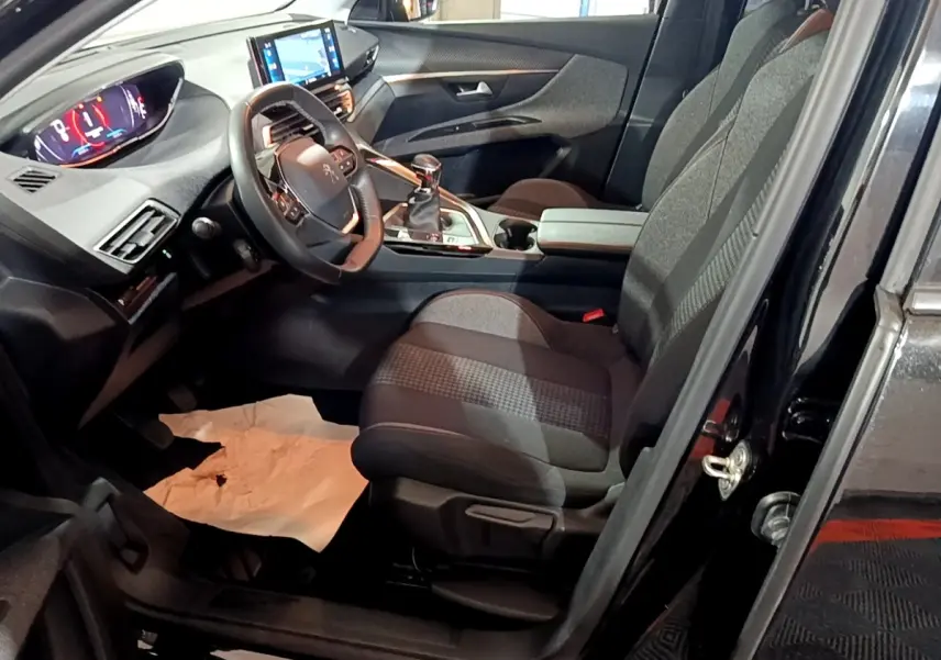 Vue intérieure côté conducteur du Peugeot 5008 noir, avec tableau de bord digital et écran tactile central visible.