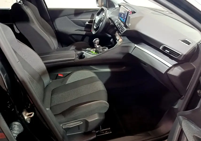 Vue intérieure côté passager avant du Peugeot 5008 noir 2021, montrant sièges tissu et tableau de bord avec écran tactile.