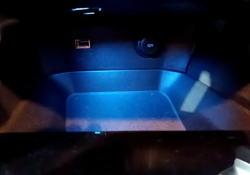 Gros plan sur la prise 12V et port USB éclairés en bleu dans le compartiment intérieur du Peugeot 5008 noir.