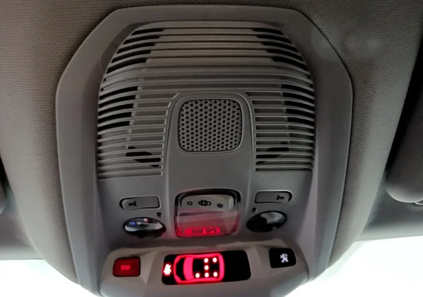 Vue en contre-plongée du plafonnier intérieur gris du Peugeot 5008 noir, avec boutons lumineux et alerte SOS rouge.