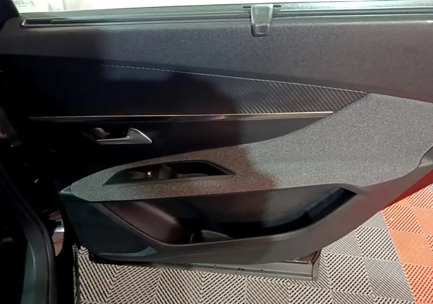 Vue rapprochée de la porte intérieure côté gauche du Peugeot 5008 noir, avec garniture tissu et insert effet carbone.