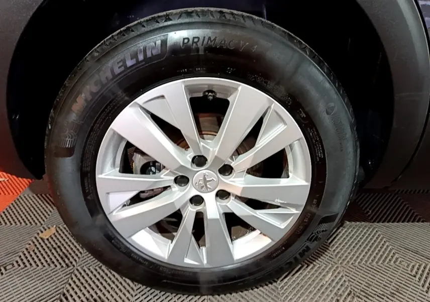 Gros plan sur la roue avant droite d’un Peugeot 5008 noir, avec jante argentée et pneu Michelin Primacy 4.