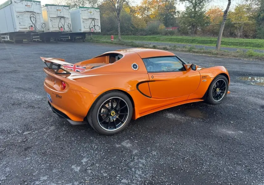 Lotus Elise 3 Cup 250 orange vue 3/4 arrière droit, jantes noires satinées et aileron avec drapeau britannique.