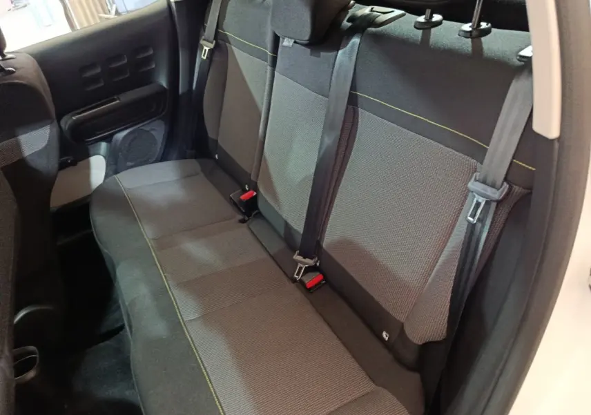 Vue intérieure de la banquette arrière grise avec surpiqûres jaunes de la Citroën C3 blanche, portes ouvertes côté droit.