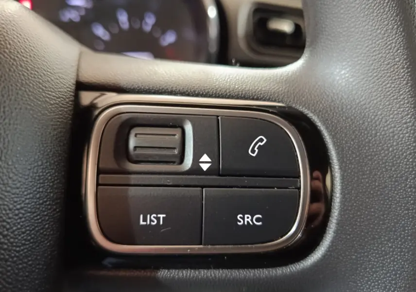 Gros plan sur les commandes multifonctions noires du volant de la Citroën C3 blanche, version Feel Business 2020.
