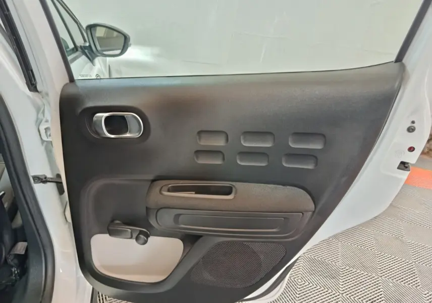 Vue intérieure de la porte arrière droite blanche d'une Citroën C3 2020 avec poignée chromée et manivelle de vitre.