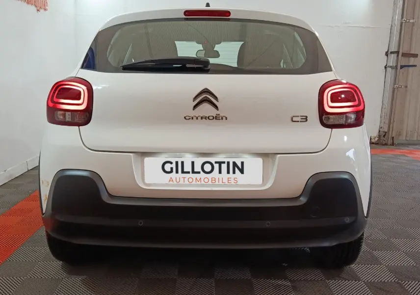 Vue arrière d'une Citroën C3 blanche de 2020 avec feux arrière allumés et pare-chocs noir contrastant.