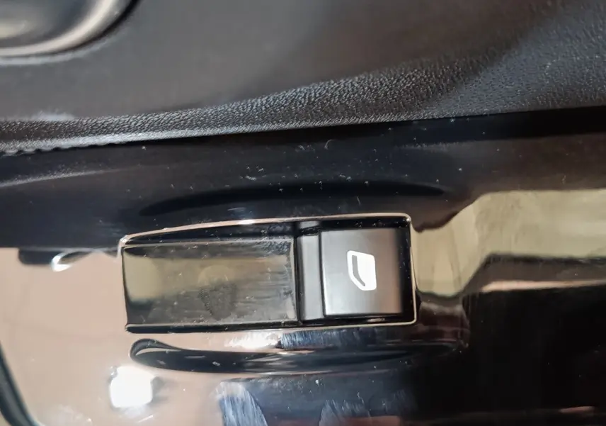 Gros plan sur le bouton de commande de lève-vitre côté conducteur de la Citroën C3 blanche, intérieur noir brillant.