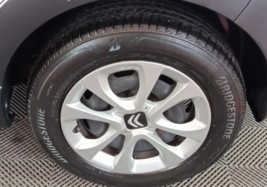 Gros plan sur la roue avant gauche d'une Citroën C3 blanche, avec jante alliage et logo Citroën au centre.