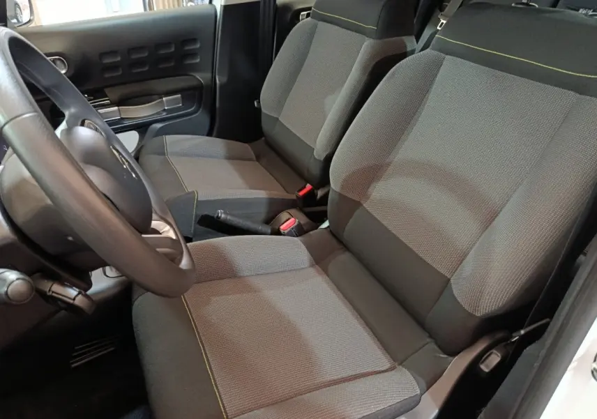 Vue intérieure côté conducteur de la Citroën C3 2020, sièges tissu gris avec surpiqûres jaunes et volant multifonctions.