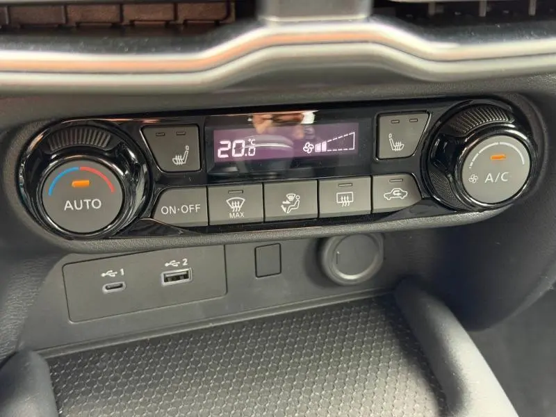 Gros plan sur la console centrale du Nissan Juke 2025 montrant les commandes de climatisation et les ports USB.