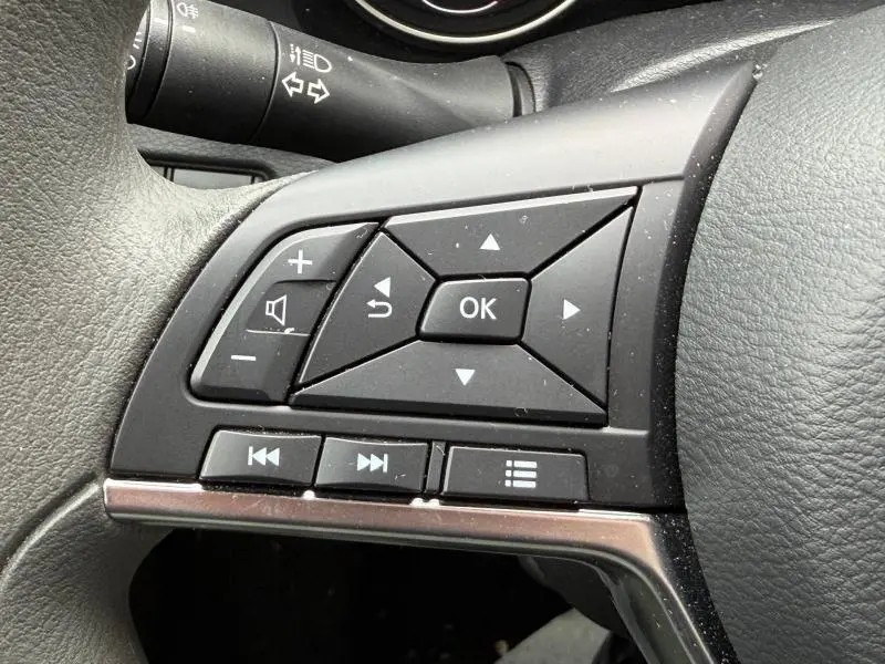 Gros plan sur les commandes multifonctions noires du volant du Nissan Juke 2025, finition Bleu Magnétique Spéciale.
