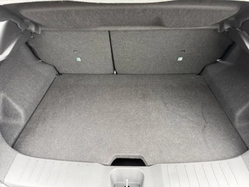 Coffre ouvert vu de l'arrière du Nissan Juke 2025, revêtement intérieur gris foncé, espace de chargement vide.
