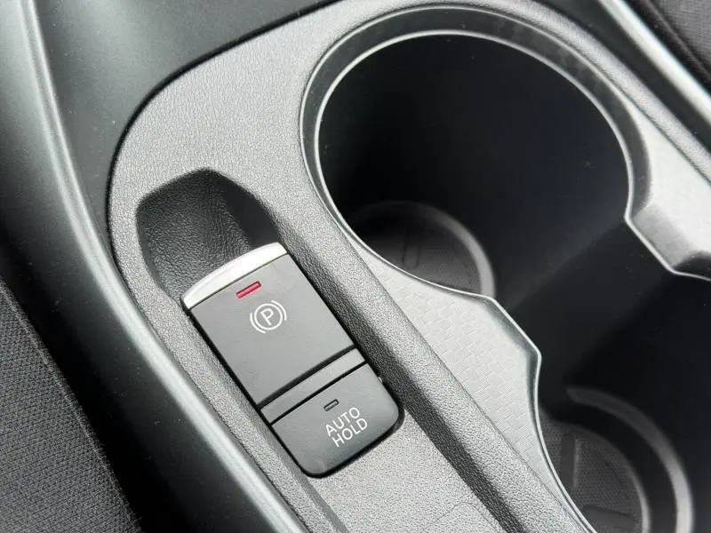 Gros plan sur la console centrale noire du Nissan Juke 2025, montrant le frein à main électrique et le bouton Auto Hold.