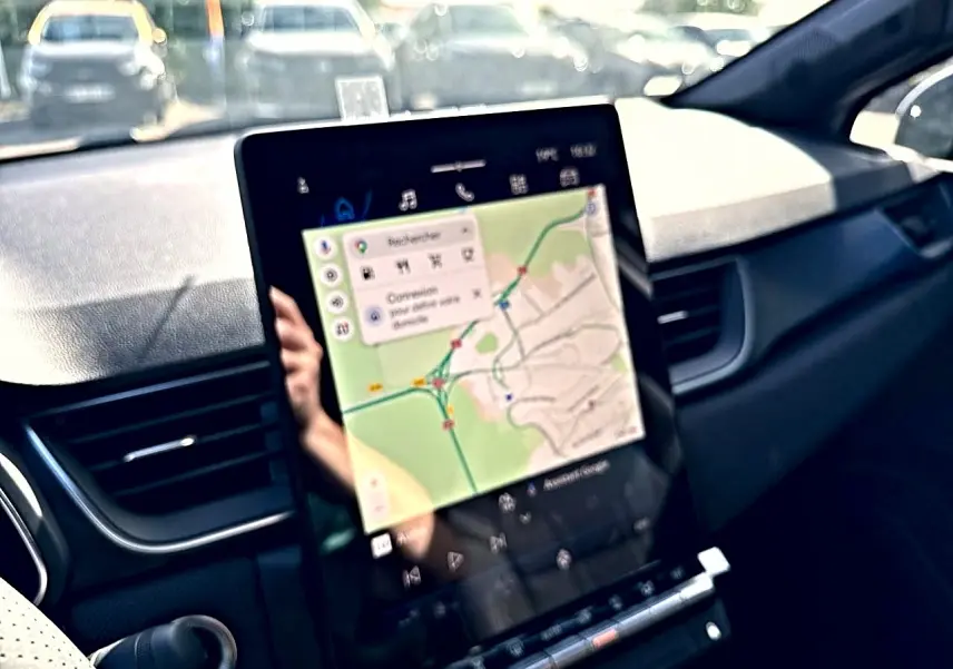Vue intérieure du tableau de bord de la Renault Symbioz gris rafale, avec écran tactile affichant un GPS cartographique.