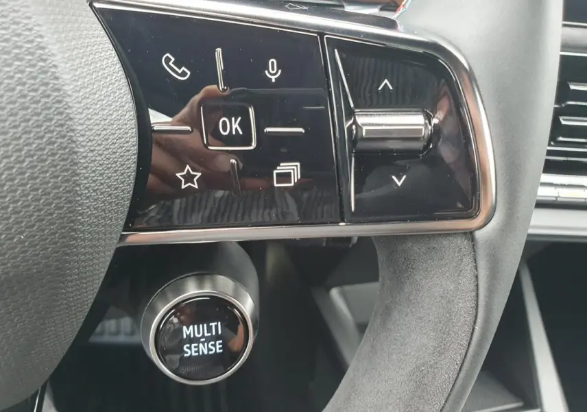 Gros plan sur les commandes multifonctions et le bouton Multi-Sense du volant de la Renault Clio VI hybride.