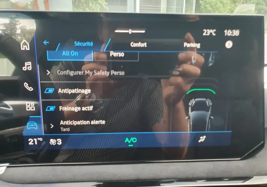 Écran tactile central de la Renault Clio VI hybride, affichant les réglages de sécurité et confort, intérieur noir.