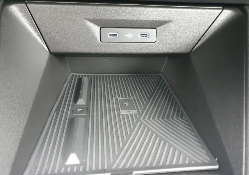 Détail de la console centrale avec deux prises USB-C rétroéclairées et surface de recharge sans fil dans une Renault Clio VI.