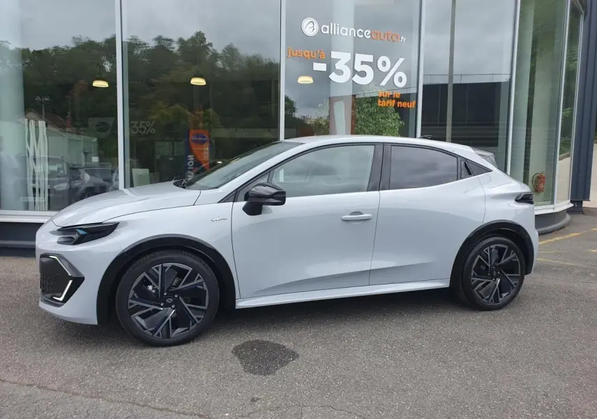 Profil droit de la Renault Clio VI 1.8 E-TECH hybride gris Rafale avec jantes alliage 18 pouces et vitres surteintées.