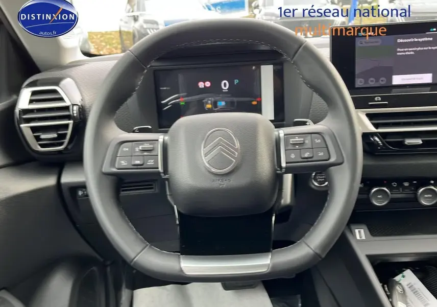 Vue centrée sur le volant cuir de la Citroën C4 1.2 hybride 2025 avec tableau de bord numérique et écran tactile.