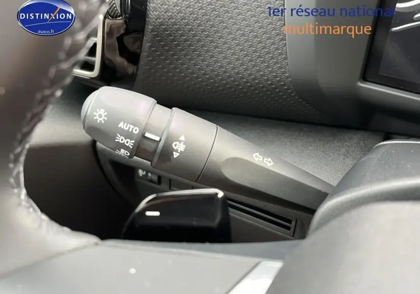 Gros plan sur la commande des feux et clignotants à gauche du volant cuir dans l’habitacle noir du Citroën C4 2025.