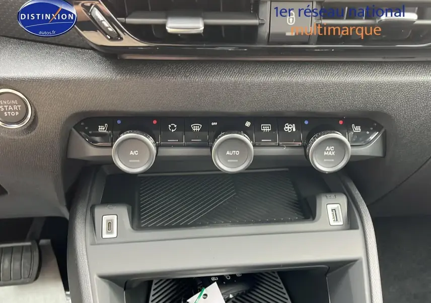 Gros plan sur la console centrale noire du Citroën C4 1.2 hybride 2025 avec commandes climatisation et bouton start/stop.