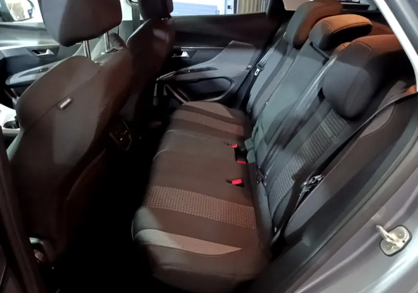 Vue côté droit sur l'intérieur arrière du Peugeot 3008 gris clair, montrant la banquette 3 places en tissu noir.