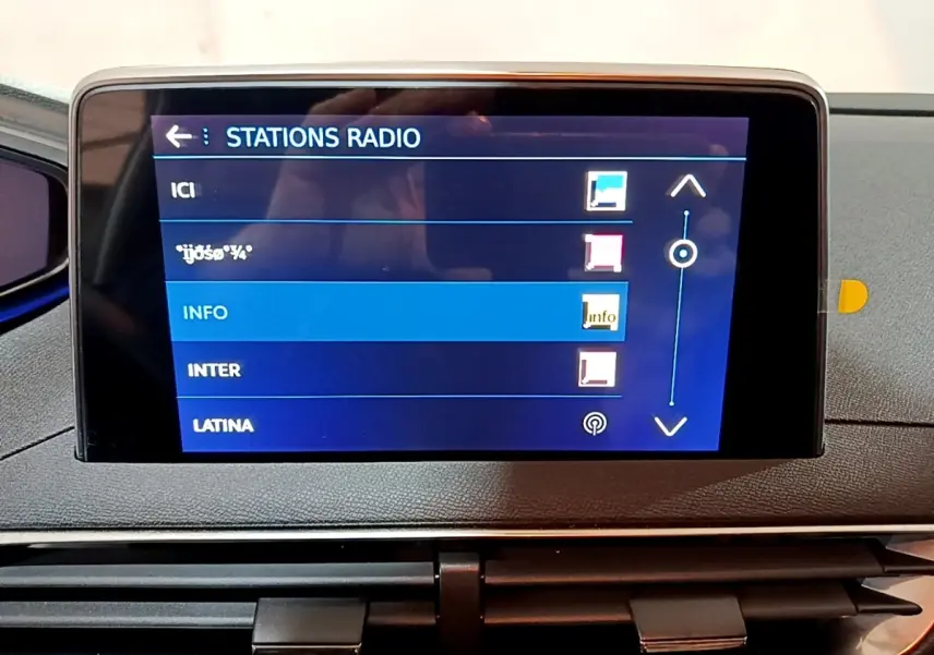 Écran tactile central affichant les stations radio dans l’habitacle d’un Peugeot 3008 gris clair, vue de face.