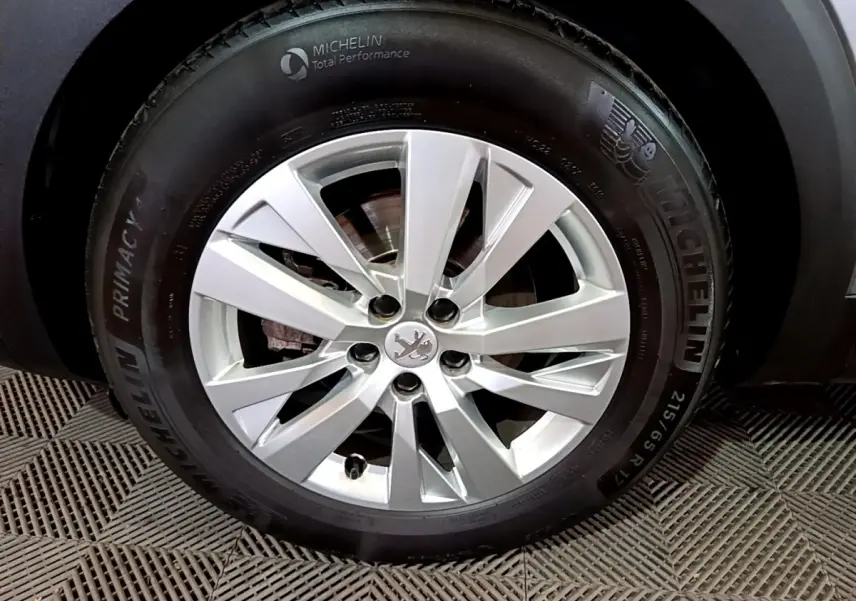 Gros plan sur la roue avant droite d’un Peugeot 3008 gris clair, jante alliage argentée et pneu Michelin.