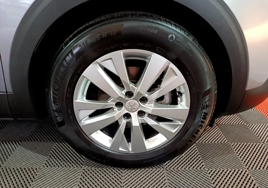 Gros plan sur la roue avant droite gris clair d’un Peugeot 3008 avec jante alliage et pneu Michelin.