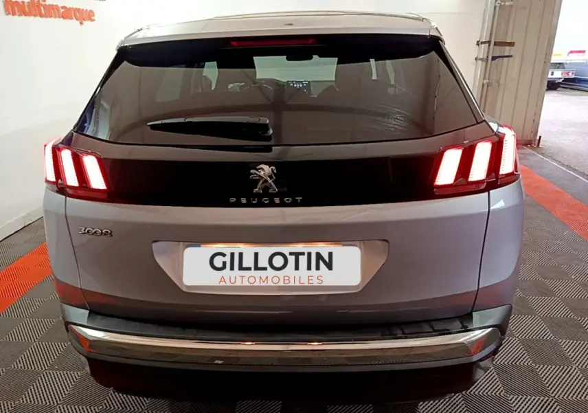 Vue arrière d’un Peugeot 3008 gris clair avec feux LED allumés dans un garage.