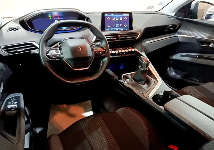 Vue intérieure avant du Peugeot 3008 gris clair 2020, mettant en valeur le volant cuir, l’écran tactile et la boîte manuelle.